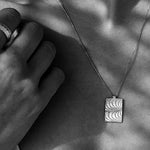 Silbernes Rechteck mit maritimen Wellen. Das Geheimnis toller Frauen lliegt in ihrer Authentizität und ihrem Mut, besonderen Schmuck zu tragen