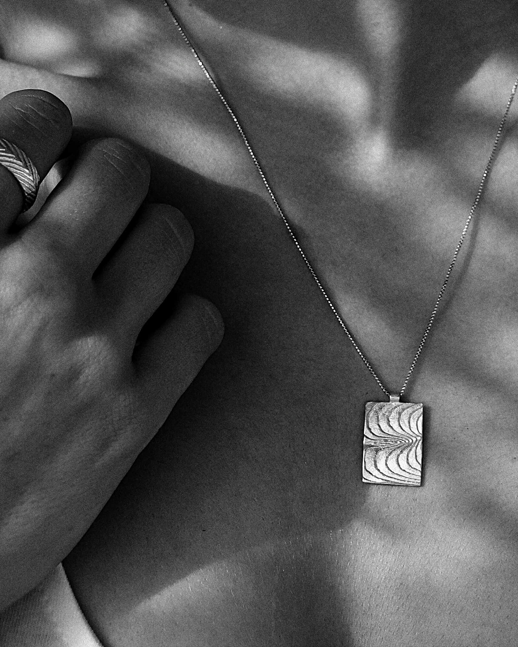 Silbernes Rechteck mit maritimen Wellen. Das Geheimnis toller Frauen lliegt in ihrer Authentizität und ihrem Mut, besonderen Schmuck zu tragen