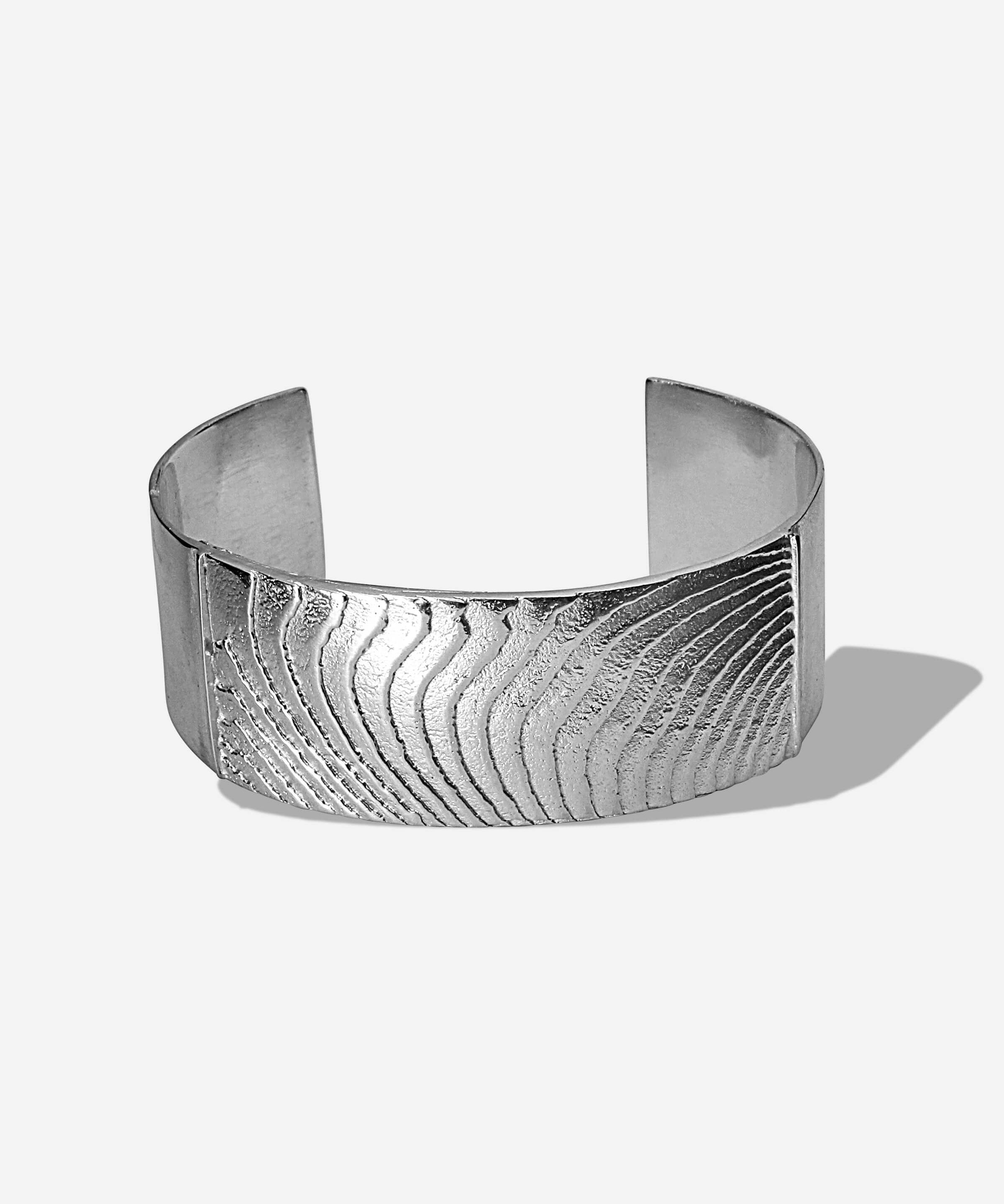 Das Dune Bracelet in Silber. Die wellenartigen Strukturen erzählen von Sediment, von Sanddünen und vom Meeresboden