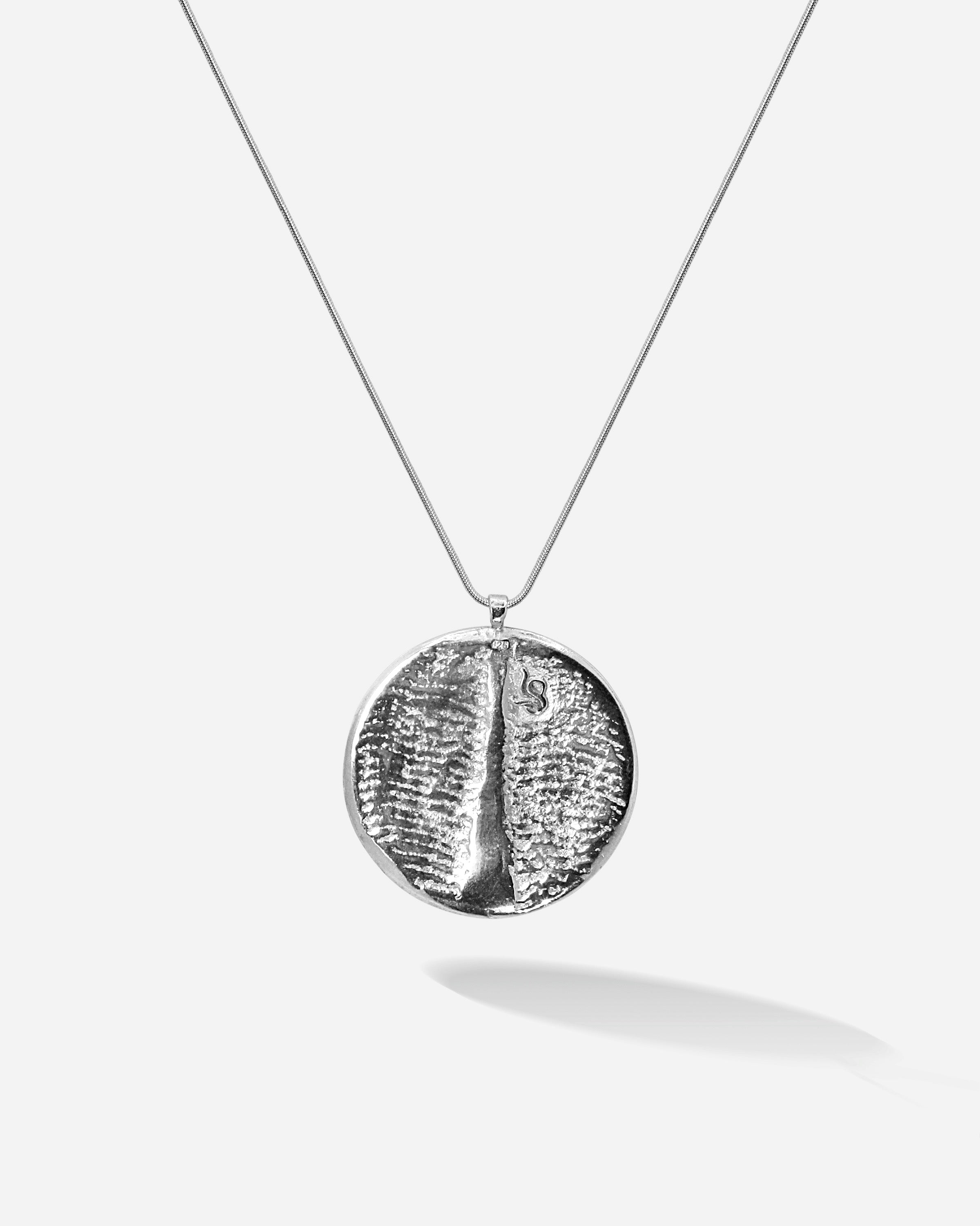 Schlicht, zeitlos und ein bisschen unglaublich, wie fein Goldschmiedekunst sein kann. Dieses silberne Amulett zeigt auch auf der Rückseite die Sepiah Struktur