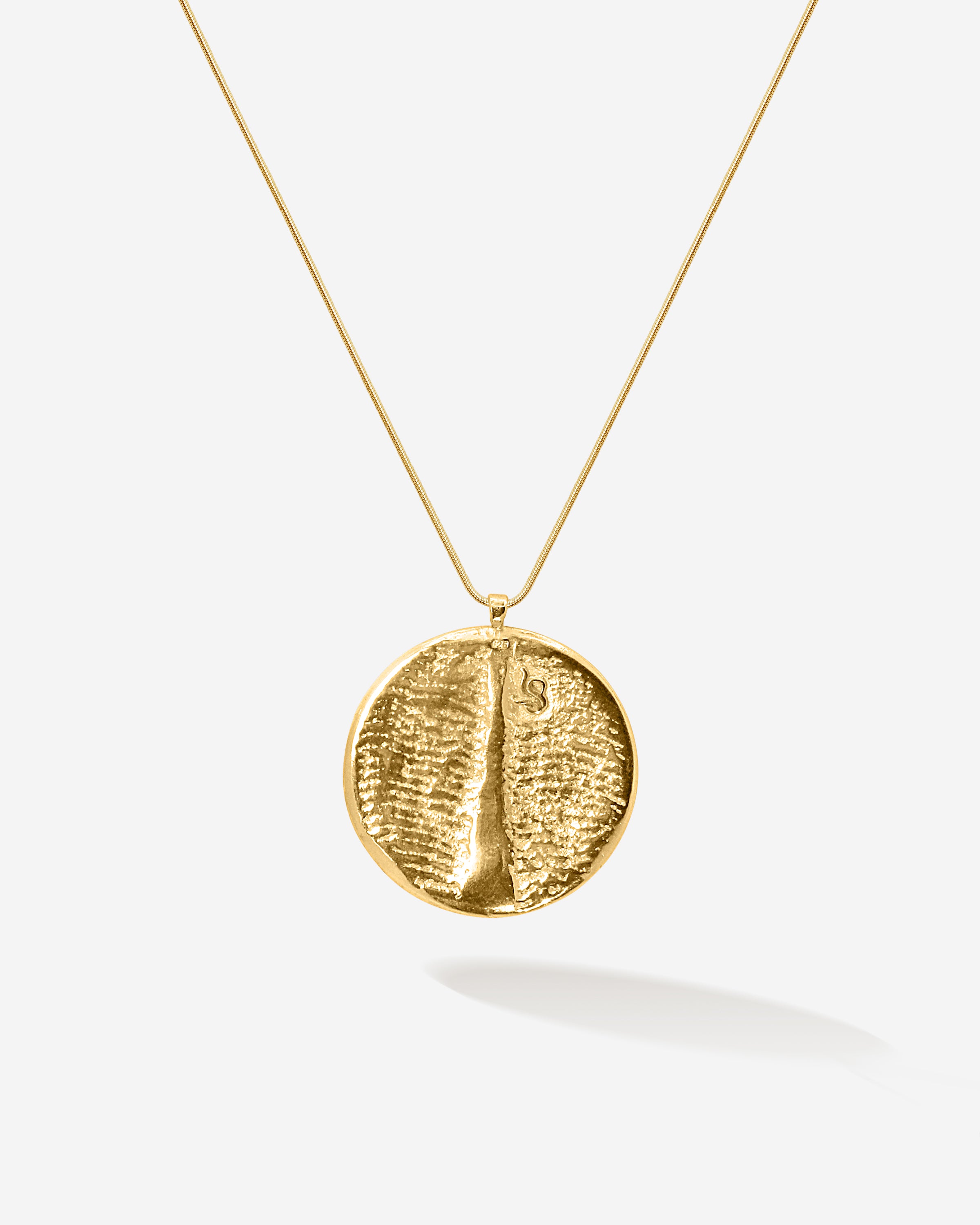 Schlicht, zeitlos und ein bisschen unglaublich, wie fein Goldschmiedekunst sein kann. Dieses goldene Amulett zeigt auch auf der Rückseite die Sepiah Struktur