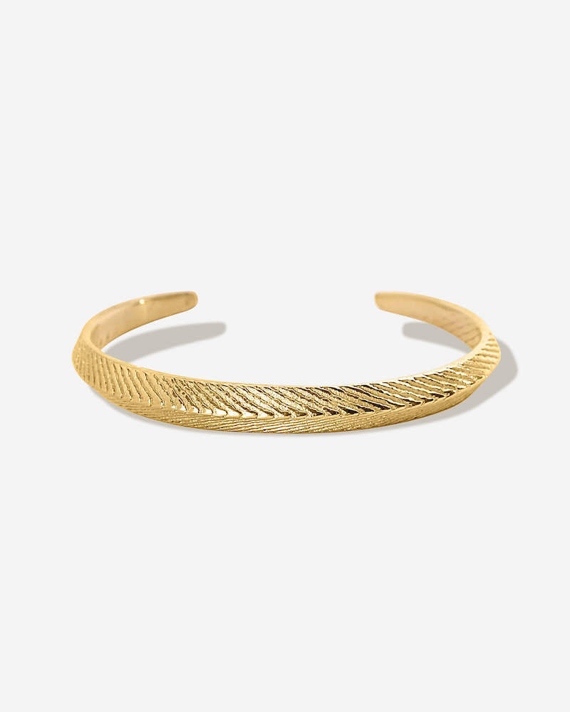 Der zierliche goldene Armreif mit feiner Meeresstruktur auf der Oberfläche, glänzt durch Schlichtheit und erinnert dich sanft an deine schönen Tage am Meer