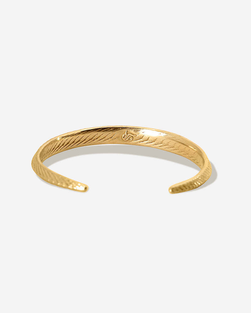 Der zierliche goldene Armreif mit feiner Meeresstruktur auf der Rückseite